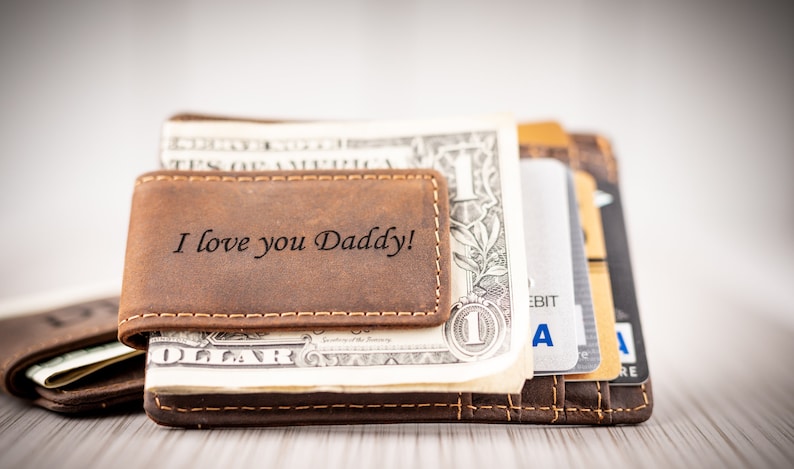 May include: A brown leather wallet with a money clip. The wallet has the words "I love you Daddy!" engraved on the front.