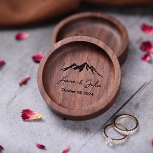 May include: A wooden ring box with a mountain range design and the text "Aaron & Julie October 08, 2024".