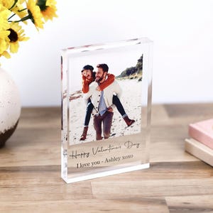 May include: A clear acrylic block photo frame with a picture of a couple on a beach. The text "Happy Valentine's Day I love you - Ashley xoxo" is printed on the frame.