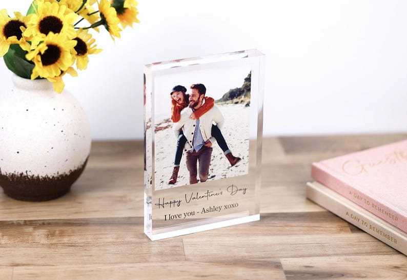 May include: A clear acrylic block photo frame with a picture of a couple on a beach. The text "Happy Valentine's Day I love you - Ashley xoxo" is printed on the frame.