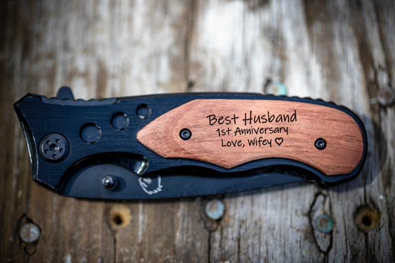 May include: A black pocket knife with a wooden handle engraved with the text "Best Husband 1st Anniversary Love, wifey".