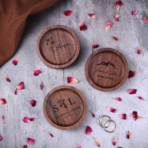 May include: Three wooden ring boxes with engraved designs. The first box has a floral design and the name "Angela" engraved. The second box has a mountain design and the text "Aaron & Julie, October 08, 2024". The third box has a floral design and the text "S&L, Shane & Lauren, 03-18-2024".