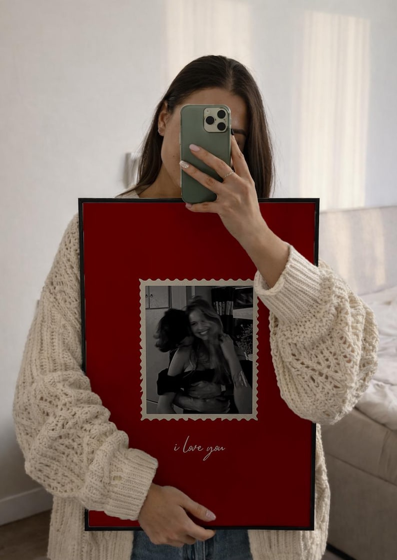 K&ouml;nnte beinhalten: Ein gerahmtes Foto mit rotem Hintergrund und schwarzem Rand. Das Foto im Inneren ist ein Schwarz-Wei&szlig;-Bild von zwei sich umarmenden Personen. Die Worte "i love you" sind unten in Kursivschrift geschrieben.