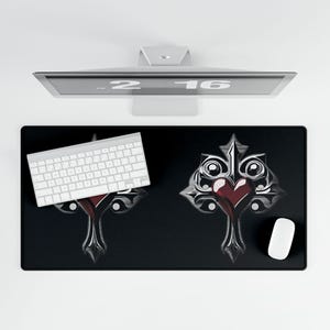 May include: Black desk mat with a decorative design featuring a red heart and ornate silver accents. A white keyboard and mouse are on the mat. A computer monitor is above the mat.