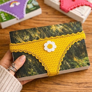 Puede incluir: Una taza de cerámica blanca con un asa negra y el texto "But First, Coffee" en negrita negra. La taza se encuentra sobre un fondo borroso, sugiriendo un ambiente acogedor.