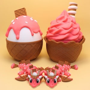 May include: Two ice cream-themed containers with brown waffle-textured bases. One has a white scoop with pink topping and a square wafer; the other has pink soft-serve and a striped wafer. Two small pink dragon figurines with wafer accents.