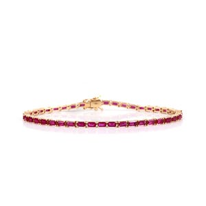 Pode incluir: Uma pulseira dourada com uma linha de pedras preciosas retangulares vermelho escuro. A pulseira é exibida em um fundo branco, destacando o design e a cor da joia. O fecho é visível.