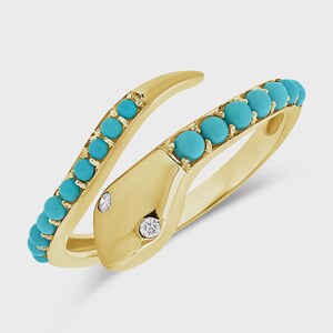 Könnte beinhalten: Ein goldener Ring in Schlangenform mit polierter Oberfläche, besetzt mit einer Reihe kleiner, runder Türkis-Cabochons entlang des Körpers und zwei klaren, funkelnden Diamanten im Rundschliff als Augen im Kopf der Schlange.