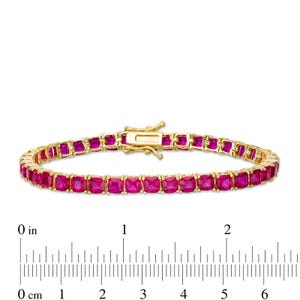 May include: A gold-toned bracelet featuring a row of square-cut, vibrant pink gemstones. The bracelet is secured with a gold clasp. The ruler shows the bracelet is approximately 6 inches long.
