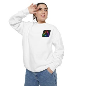 May include: A white long-sleeve sweatshirt featuring a small, square graphic on the left chest. The graphic displays a vibrant, multicolored triangle with a glowing, electric effect set against a solid black background, contrasting with the fabric.