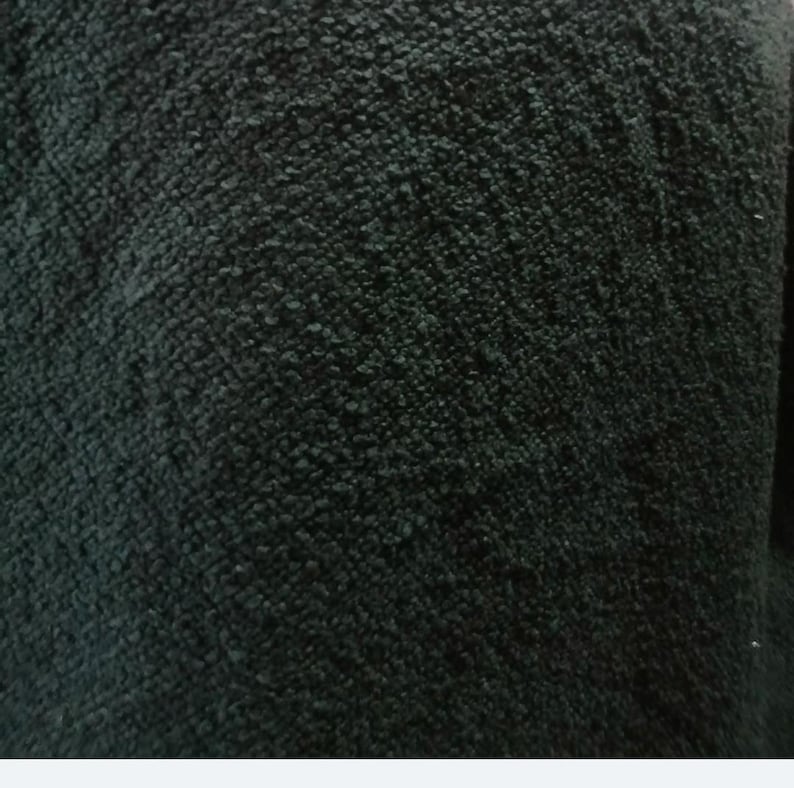 Op de afbeelding: Een donker antracietzwarte stof met een dicht, noppig en sterk getextureerd oppervlak. Het materiaal heeft een consistente constructie met lussen die een diep, onregelmatig en tactiel uiterlijk cre&euml;ert over het gehele zichtbare deel van het textiel.