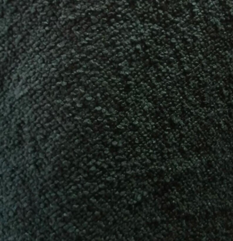 Op de afbeelding: Een donkergroene stof met een dicht, gestructureerd en gelust oppervlak. Het materiaal heeft een consistent, uniform weefpatroon over het geheel, wat zorgt voor een zachte en tactiele uitstraling met diepe schaduwen tussen de individuele lussen.