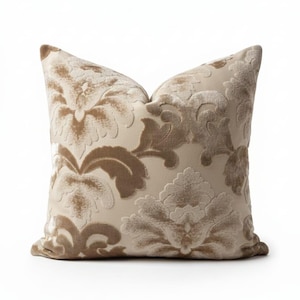 May include: A decorative pillow with a beige background and a raised floral pattern in shades of brown. The pillow has a soft, textured appearance and a classic design, suitable for home decor.