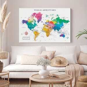 May include: A rectangular wall art print titled WORLD ADVENTURES featuring a colorful world map with watercolor-style gradients in pink, blue, green, and yellow. The map includes a compass rose and text details on a white background.