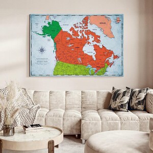 May include: A rectangular wall map print featuring North America with Canada in orange, the United States in light green, and Alaska in dark green. The map includes a compass rose, geographic labels, and the text Adventure Awaits in the lower left corner.
