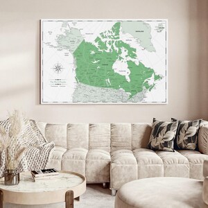May include: A rectangular wall map print featuring a light green highlighted Canada centered against a pale grey background. The map includes detailed geographical labels, a compass rose, and the text The World Awaits in the lower left corner.