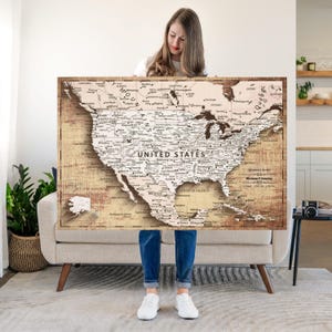 May include: A large rectangular wall map of North America featuring the United States, Canada, and Mexico. The map has a vintage-style sepia-toned background with black text detailing cities, states, and geographical features across the continent.