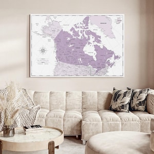 May include: A wall-mounted map print featuring a light purple and white color scheme. The map highlights Canada and surrounding regions with clear text labels, a compass rose, and the title The World Awaits printed in the lower left corner.