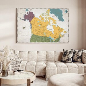 May include: A wall map of Canada and surrounding regions featuring a color-coded design with yellow for Canada, purple for Alaska, and green for the northern United States. The map includes a compass rose, geographic labels, and a border frame.
