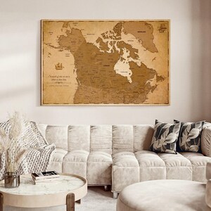May include: A rectangular wall map of Canada and surrounding regions printed in shades of brown and tan on a textured background. The map features detailed geographical labels, a compass rose, and the text "So much of who we are is where we have been."