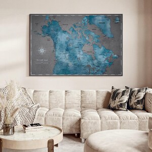 May include: A rectangular wall map of North America featuring a dark gray background with blue-toned landmasses. The map includes detailed geographical labels, a compass rose in the lower left corner, and the text The World Awaits printed below it.