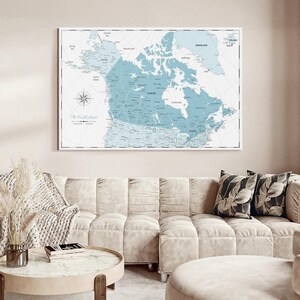 May include: A rectangular wall map print featuring a light blue color palette, depicting the geography of Canada and surrounding regions. The map includes detailed labels for cities, provinces, and bodies of water, with a compass rose in the corner.
