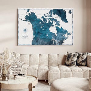 May include: A rectangular wall art print featuring a stylized map of North America in shades of deep blue and white. The map displays geographical labels, a compass rose, and the text My World. The print is enclosed in a thin white frame.