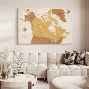 May include: A rectangular wall map of North America featuring a muted color palette of tan, beige, and brown tones. The map displays geographical borders, major cities, and bodies of water, with a compass rose in the lower left corner.