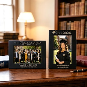 May include: Two black photo frames displaying graduation pictures. One frame shows a group photo with "Class of 2026" and "Jayden Teller, Rochester High School." The other frame features a graduate with "Class of 2026" and "Madison Bennett, North Hills High School."