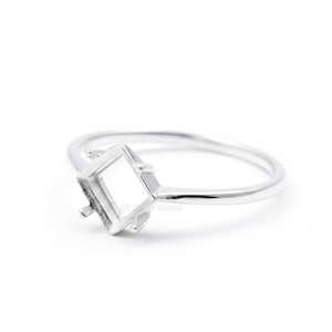 May include: A silver ring with a square setting. The ring's band is thin and smooth, leading to a square setting designed to hold a gemstone. The setting has small prongs to secure the stone. The ring is shown against a white background.