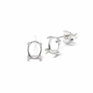 May include: Two silver-colored oval stud earring settings. The settings have four prongs to hold a gemstone. The earrings are on a white background.