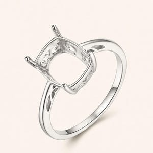 May include: A silver-toned metal ring setting featuring a four-prong head designed to hold a square-shaped gemstone. The band and the gallery of the setting display intricate, openwork filigree patterns along the sides of the metal structure.