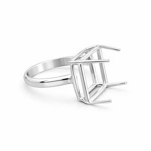 Puede incluir: Un engaste de anillo plateado con un diseño de jaula cuadrada. El anillo presenta una banda lisa y pulida y un engaste geométrico diseñado para sostener una piedra preciosa cuadrada. El anillo se muestra sobre un fondo blanco.