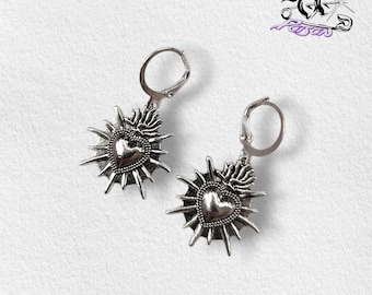 Brincos de argola Sagrado Coração - prata: argolas em aço inoxidável com pingentes de coração sagrado em liga de zinco representando raios de sol.