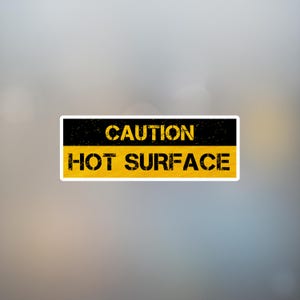 Può includere: Un adesivo rettangolare con una combinazione di colori nero e giallo. La sezione superiore è nera con la parola "CAUTION" in giallo, carattere usurato. La sezione inferiore è gialla con le parole "HOT SURFACE" in nero, carattere usurato.