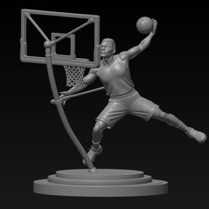 Puede incluir: Escultura gris de un jugador de baloncesto en pleno mate, sosteniendo el balón por encima de su cabeza. El jugador lleva camiseta y pantalón corto, con una canasta de baloncesto de fondo. La escultura está sobre una base redonda.