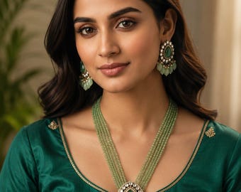 May include: A multi-strand necklace featuring light green beads and a central teardrop-shaped pendant with a green stone surrounded by small white accents and dangling beads, paired with matching teardrop-shaped earrings in the same design.