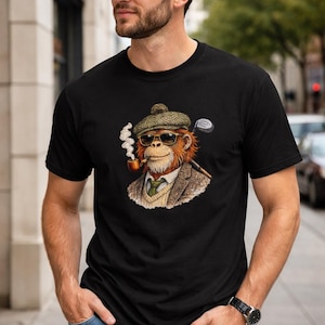 Puede incluir: Camiseta negra con una ilustración detallada de un mono con gafas de sol, gorra de tweed y blazer, fumando en pipa, con un palo de golf. El mono es el foco central del diseño.