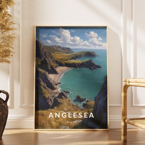 Puede incluir: Un cuadro enmarcado de Anglesey, Gales, con un paisaje costero con agua turquesa, acantilados y una playa de arena bajo un cielo azul con nubes. El cuadro está en un marco dorado y se apoya en una pared blanca. El texto "Anglesea Wales" es visible.