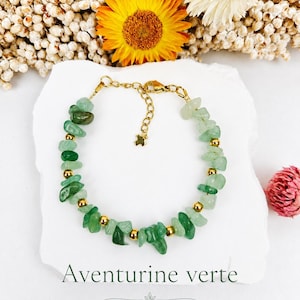 Peut inclure: Un bracelet composé de pierres d'aventurine verte irrégulières alternées avec de petites perles métalliques dorées. Le bijou comporte une chaîne dorée avec un fermoir mousqueton et une breloque en forme d'étoile. Texte Aventurine verte Chance.