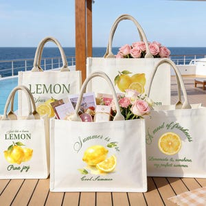 May include: A collection of off-white canvas tote bags with beige handles. Each bag features a lemon-themed design with text such as "Lemon", "Summer is here", and "A mood of freshness". Some bags contain pink roses and small gifts.