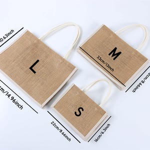 Pu&ograve; includere: Tre borse tote rettangolari in iuta con manici bianchi. Le borse sono etichettate L, M e S. La borsa pi&ugrave; grande &egrave; lunga 38 cm, la borsa media &egrave; lunga 33 cm e la borsa pi&ugrave; piccola &egrave; lunga 22 cm.