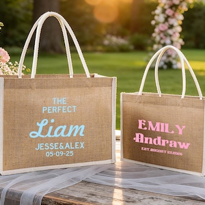 Pu&ograve; includere: Due borse tote in juta con manici e finiture bianche. Una borsa ha "The Perfect Liam" in testo blu, con nomi e una data sotto. L'altra borsa ha "Emily Andraw" in testo rosa, con una data sotto.