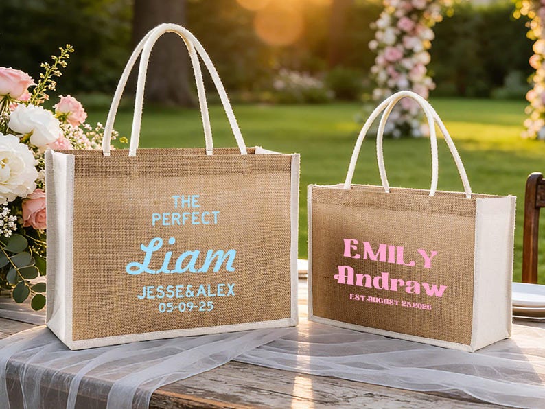 Pu&ograve; includere: Due borse tote in juta con manici e finiture bianche. Una borsa ha "The Perfect Liam" in testo blu, con nomi e una data sotto. L'altra borsa ha "Emily Andraw" in testo rosa, con una data sotto.