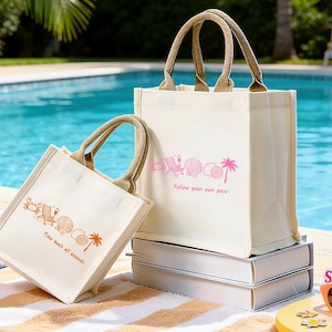 May include: Two cream canvas tote bags with brown handles. One bag features a pink beach-themed graphic and the text "Follow your own pace." The other bag has a similar graphic and the text "Time heals all wounds."
