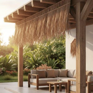 Può includere: Un patio in legno con una sporgenza del tetto di paglia. Il patio presenta un divano componibile di colore chiaro con cuscini marroni, un tavolino in legno e un rigoglioso giardino verde sullo sfondo. La scena è immersa nella calda luce del sole.