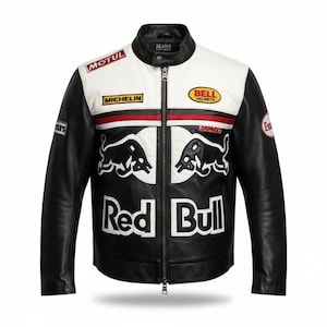 Puede incluir: Chaqueta de cuero en blanco y negro con cuello alzado y cremallera. Cuenta con parches con los logotipos de "Motul", "Michelin" y "Bell Helmets". La parte delantera muestra el logotipo de "Red Bull" y dos ilustraciones de toros.