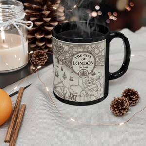 May include: A black ceramic mug featuring a vintage-style map of The City of London, Est. 1666. The design includes a circular emblem with the text, a coat of arms, and detailed illustrations of historical ships and landmarks on a cream background.