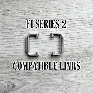May include: Two silver-coloured metal links, designed in a rectangular shape, are displayed against a light wood-grain background. The text "FI SERIES 2" and "COMPATIBLE LINKS" are printed above and below the links.
