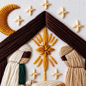 May include: A hand-embroidered scene on white fabric featuring a dark brown triangular roof structure, a golden crescent moon, and several four-pointed stars. Below the roof, two figures in cream and tan robes flank a central golden star.